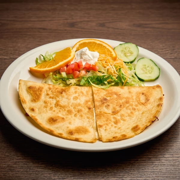 Golden-brown quesadilla halves with a side salad of lettuce, tomatoes, cheese, sour cream, orange, and cucumbers.